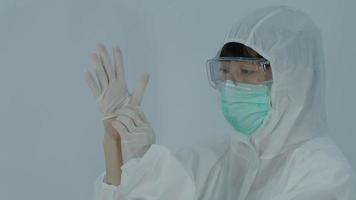 un médecin avec un EPI et un masque porte un gant pour les mains en caoutchouc nitrile.