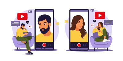 Woman and man video bloggers sitting on sofa with phone and recording video with smartphone. Different social media icons. Vector illustration in flat style.