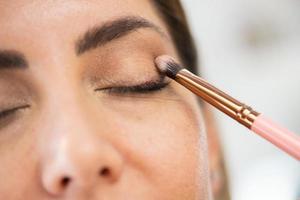 Close-up of a make-up artist applying eye shadow to her client. photo