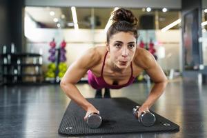 Mujer haciendo ejercicio de flexiones con mancuernas en un entrenamiento físico foto