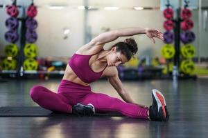 Mujer joven haciendo ejercicios de estiramiento sobre una estera de yoga foto