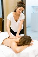 Female masseuse giving a back massage to a woman in a beauty parlour. photo