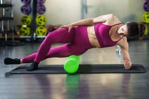 Woman relaxing her leg muscles with a green foam roller photo