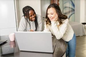 Two college girls studying together at home with laptops while drinking coffee photo