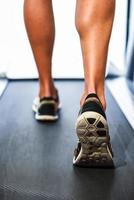 Male muscular legs running on the treadmill at the gym. photo