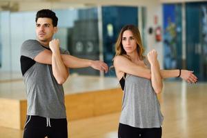 Two people stretching their arms in gym. photo