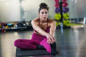 Mujer joven haciendo ejercicios de estiramiento sobre una estera de yoga foto