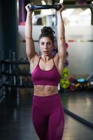 Mujer atlética haciendo flexiones de tríceps con una placa de barra