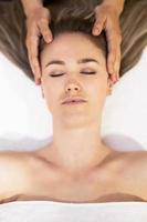 Young blond woman receiving a head massage in a spa center. photo