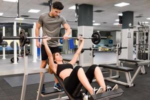 Personal trainer helping a young woman lift weights photo