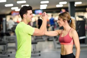 Smiling young man and woman doing high five in gym photo