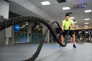 Man with battle ropes exercise in the fitness gym. photo