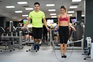 Entrenamiento de hombre y mujer con saltar la cuerda en el gimnasio crossfit