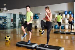 dos personas trabajando con steppers en el gimnasio. foto