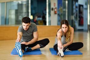 dos personas estirando sus piernas en el gimnasio. foto