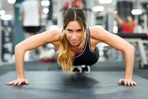 Young beautiful woman doin pushups in the gym. photo