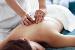 mujer joven que recibe un masaje de espalda por un terapeuta profesional. foto