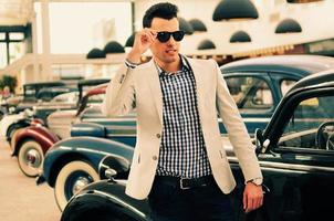 Attractive man wearing jacket and shirt with old cars photo