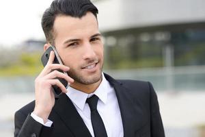 atractivo joven empresario por teléfono en un edificio de oficinas foto