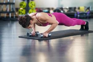 Woman doing push-ups exercise with dumbbell in a fitness workout photo