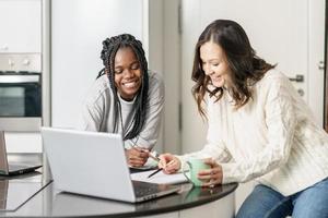 Two college girls studying together at home with laptops while drinking coffee photo