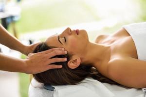 Young smiling woman receiving a head massage in a spa center. photo