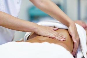 Professional female physiotherapist giving shoulder massage to blonde woman  stock photo