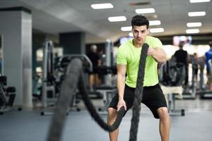 hombre con cuerdas de batalla ejercicio en el gimnasio. foto