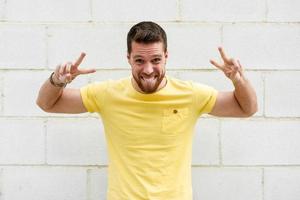 Funny young man on brick wall with funny expression. photo