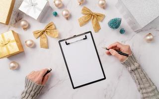 top view hands writing new year goals, resolution or shopping list on a blank paper. Mock up design photo