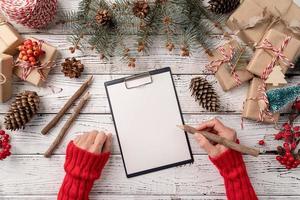 vista superior manos escribiendo metas de año nuevo, resolución o lista de compras en un papel en blanco. maqueta de diseño foto
