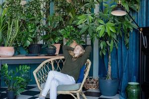 Young blonde woman sitting in comfortable chair surrounded with plants photo