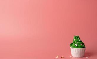 Christmas tree shaped cupcakes on pink background photo