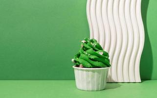 Christmas tree shaped cupcakes on white podiums green background photo