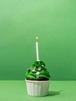 Christmas tree shaped cupcakes on green background photo
