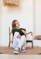 Attractive young woman sitting on the chair in light and airy interior photo