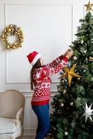 Happy young woman decorating christmas tree photo