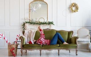 Young woman lying on couch alone in a decorated for Christmas living room photo