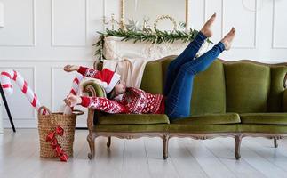 Young woman lying on couch alone in a decorated for Christmas living room photo