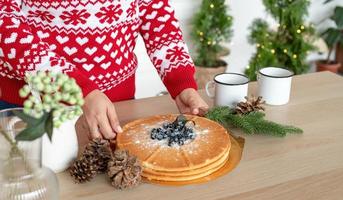 Feliz joven en Navidad suéter haciendo bebidas calientes en la cocina foto