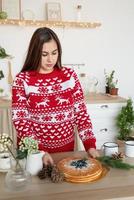 Happy young woman in christmas sweater making hot drinks in the kitchen