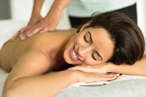 mujer joven recibiendo un relajante masaje de espalda en un centro de spa. foto