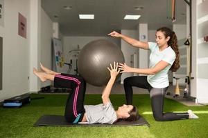 Physical therapist assisting young caucasian woman with exercise photo