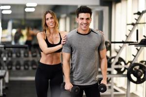 Personal trainer helping a young man lift weights photo