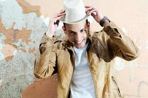 Attractive young man smiling with a hat in urban background photo