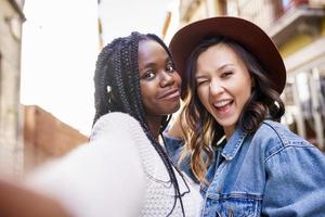 Dos hermosas mujeres multiétnicas haciendo selfie y haciendo muecas.