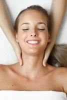 mujer joven recibiendo un masaje de cabeza en un centro de spa. foto