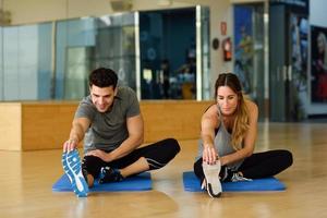 Two people streching their legs in gym. photo