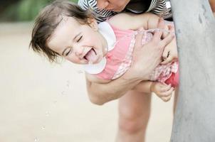 niña bebiendo agua en una fuente del parque foto