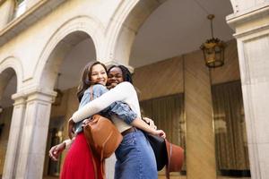 Two friends happy to see each other on the street hugging. photo